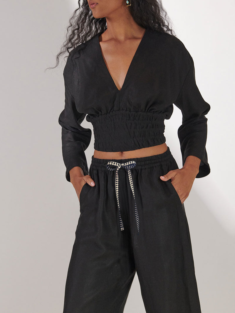 Woman Standing Wearing lemlem Aurora Plunge Top and Desta Pants in black color