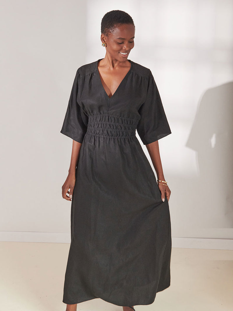 Woman standing wearing lemlem Kelemi Black Hermona Plunge Dress
