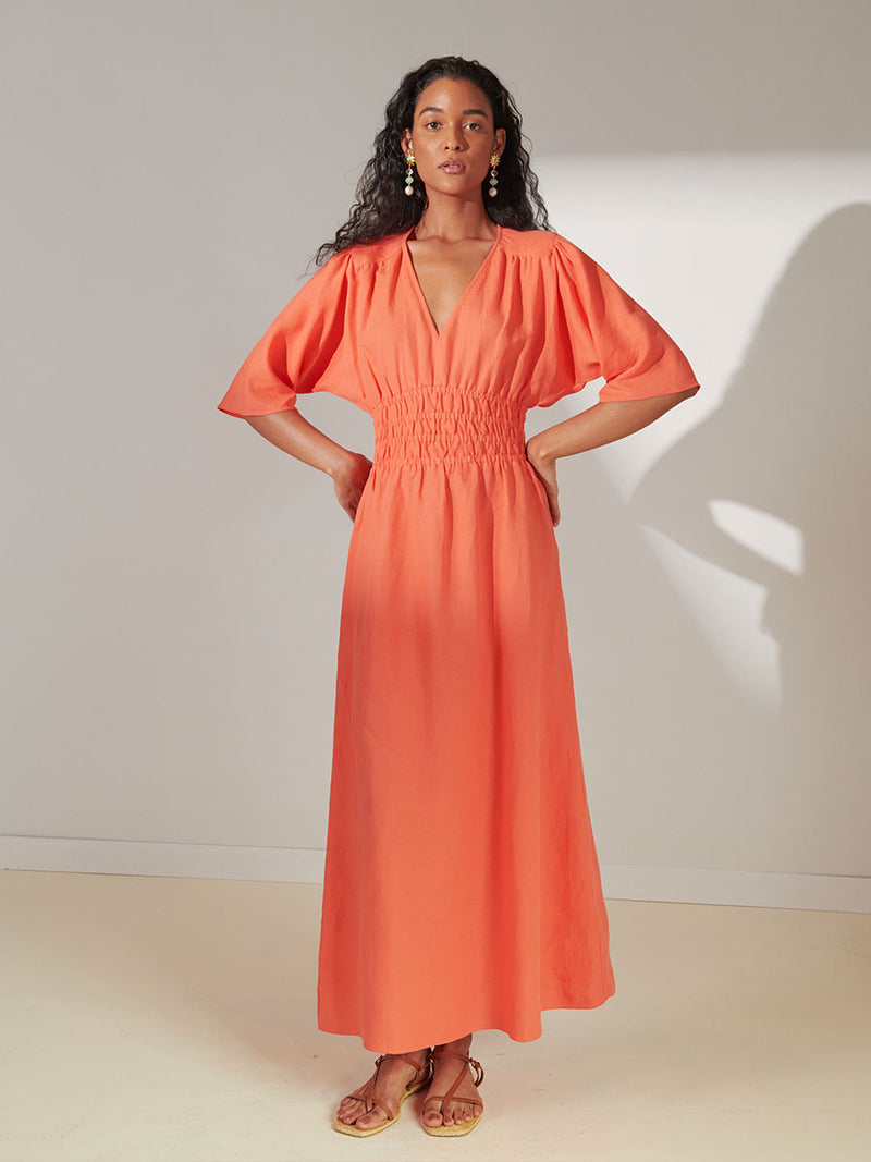 Woman Standing Wearing lemlem Hermona Plunge Dress in Coral Color
