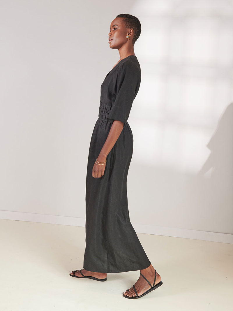 Side View of a Woman standing wearing lemlem Kelemi Black Hermona Plunge Dress