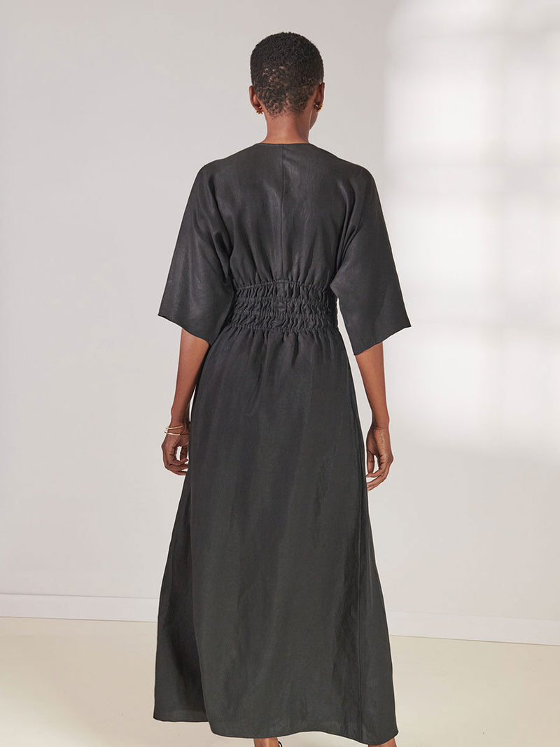 Back View of a Woman standing wearing lemlem Kelemi Black Hermona Plunge Dress