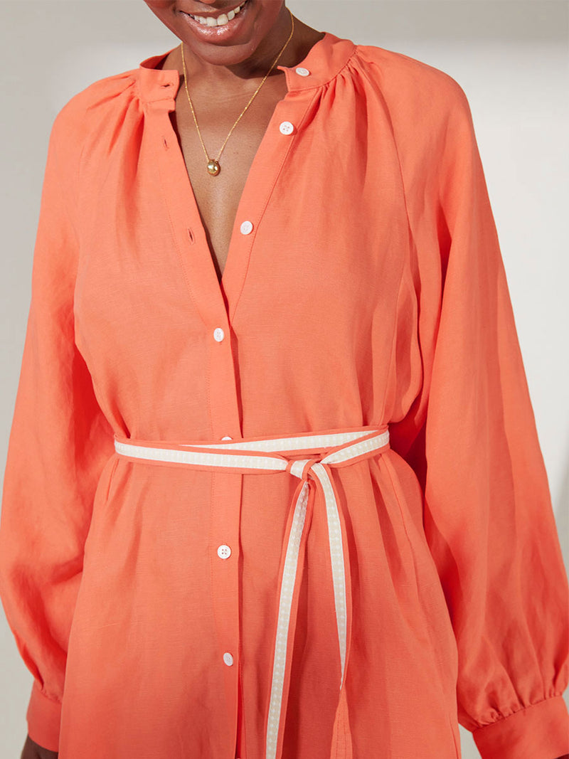 Close Up on a Woman Standing Wearing lemlem Meaza Button Up Dress in Coral Color