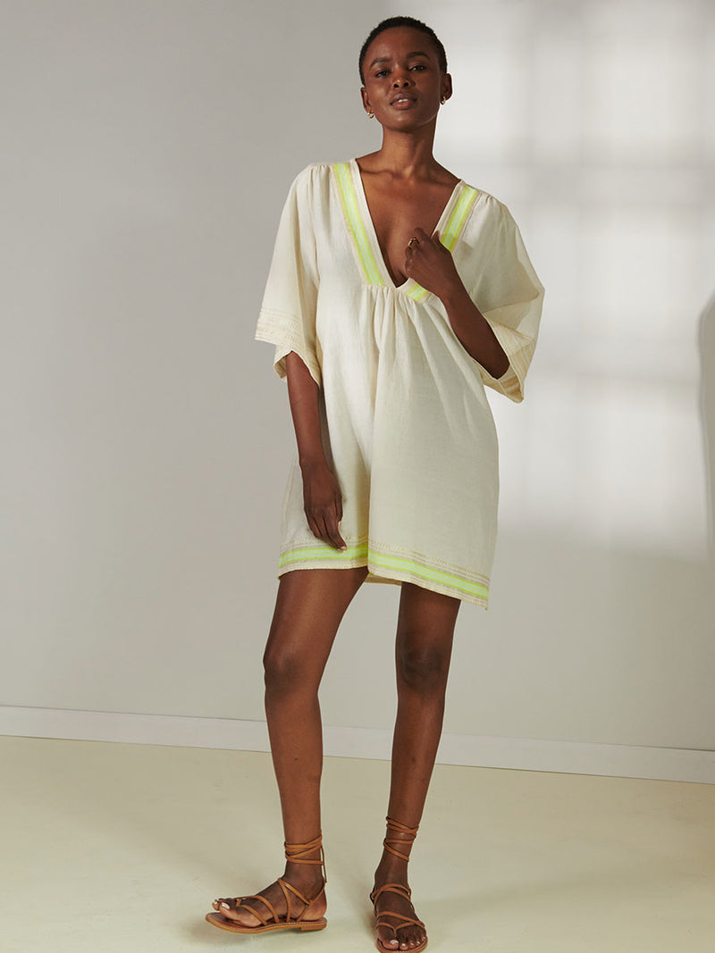 Woman Standing Wearing lemlem Belkis V Neck Caftan featuring combination of matte and shine natural tibebs and stripes in Vanilla Cream and Lime sorbet colors.