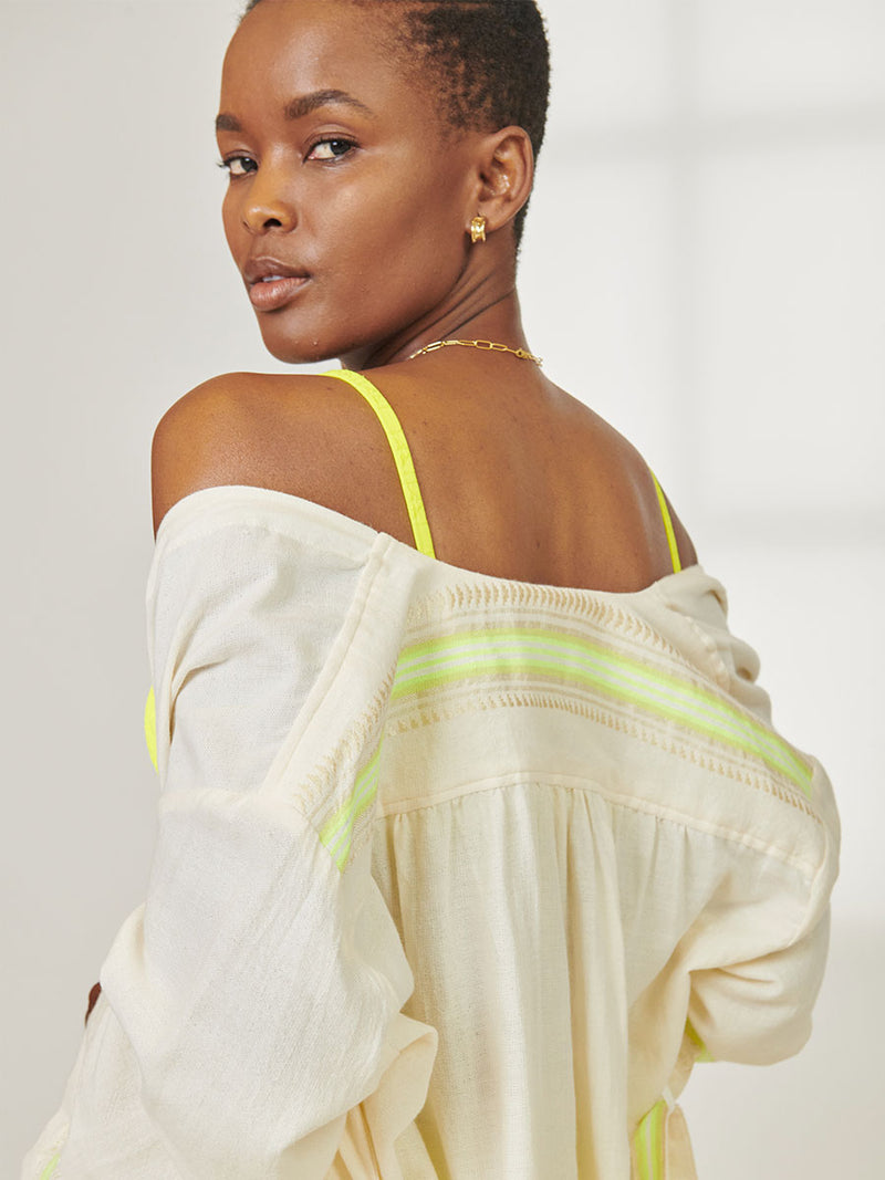 Close up on a Back of Woman Standing wearing lemlem Imani Short Robe featuring combination of matte and shine natural tibebs and stripes in Vanilla Cream and Lime sorbet colors and Jordanos Citron Scoop Top 