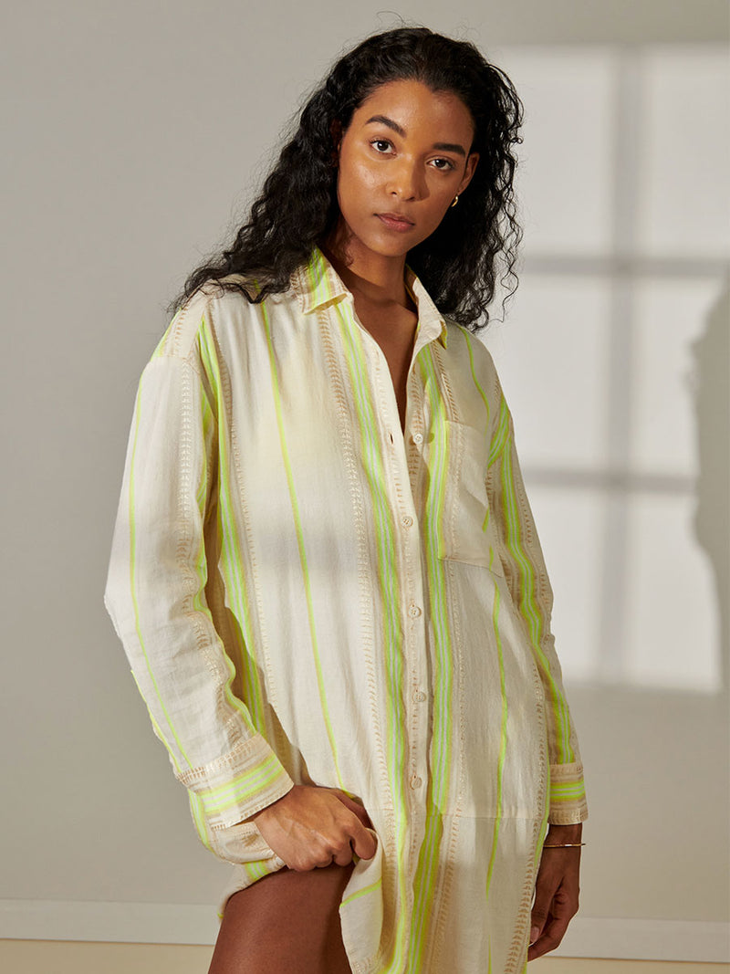 Woman Standing Wearing lemlem Mariam Shirt featuring combination of matte and shine natural tibebs and stripes in Vanilla Cream and Lime sorbet colors