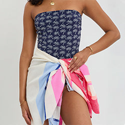 Woman wearing a strapless top with horse pattern and colorful skirt on a plain background