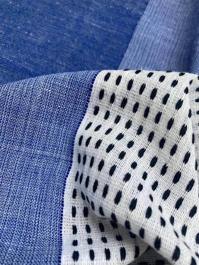 Close up on Sisay Blue Fabric Featuring textural dot pattern that contrasts the asymmetrical color-blocking of denim blues.