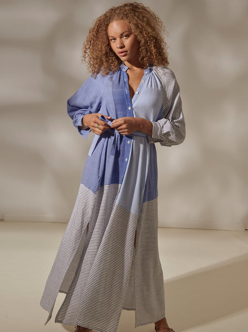 Woman Standing Wearing Makeda Button Up Dress Featuring textural dot pattern that contrasts the asymmetrical color-blocking of denim blues.