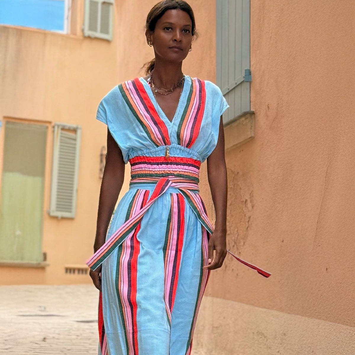 Liya Kebede walking wearing lemlem handwoven plunge top and maxi wrap skirt featuring stiped pattern in multi colors