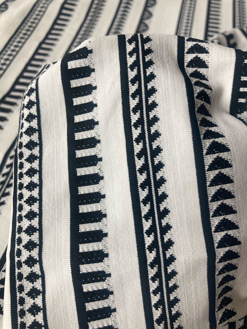 Close Up on a lemlem Yani Swim Fabric featuring intricate black Tibeb bands on a textured white background and a matching Bandeau Top