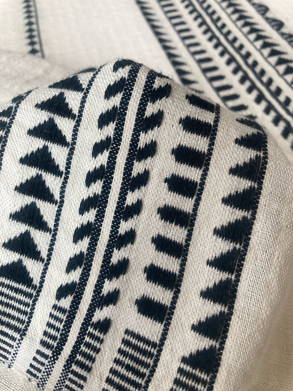 Close up on a Yani Black Fabric featuring intricate black Tibeb bands on a textured vanilla background