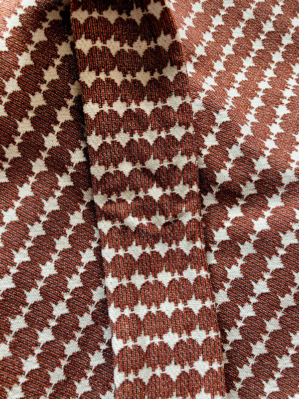 Close up on the fabric of the Zala High Leg Bikini Bottom featuring blue tibeb diamond design bands on a textured seersucker white background.  