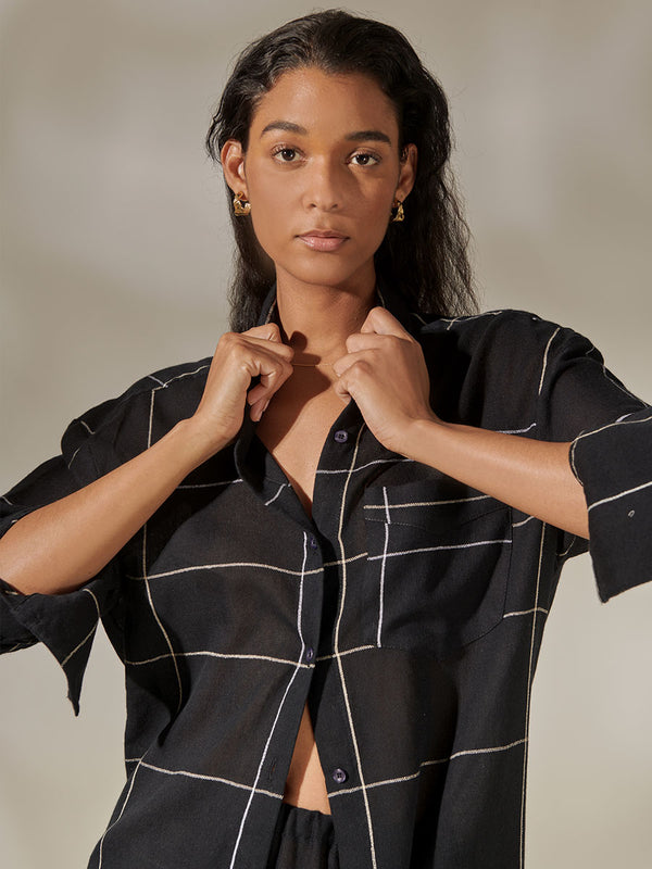Woman Standing Wearing Mariam Oversized Shirt featuring Big White Plaid Patten on Black Cotton Background