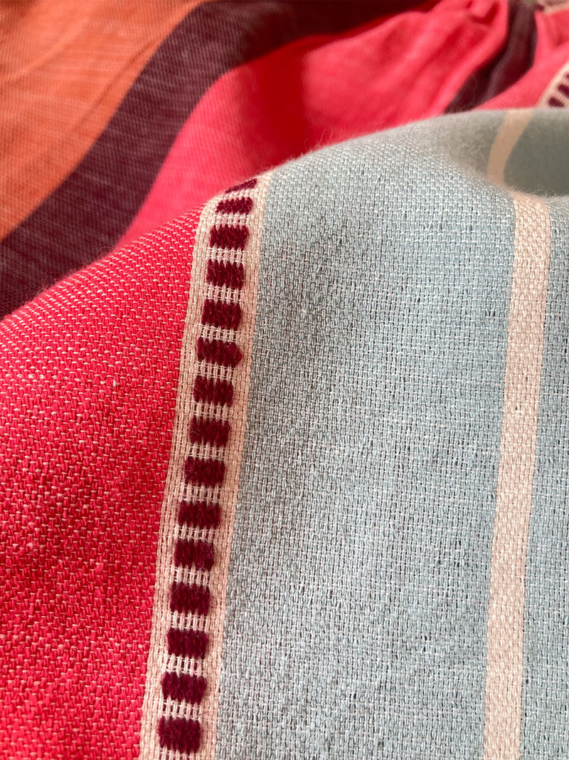 Close up on Zula Fabric featuring all over stripe color block pattern in sky, terracotta, brick and burgundy colors and matching wrap skirt