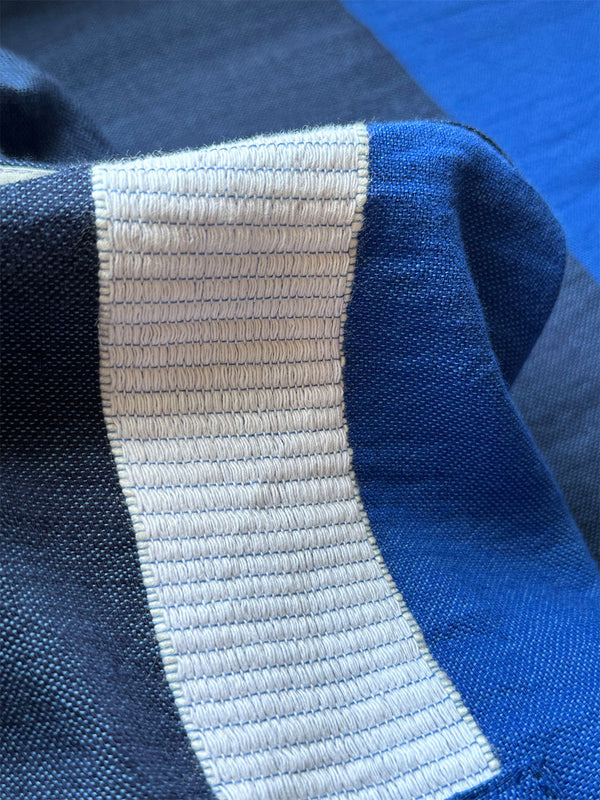 close up on betami fabric featuring a striking color-block combination of three shades of blue, paired with bands of neutral cream and white, inspired by handmade indigo quilting and African textil.