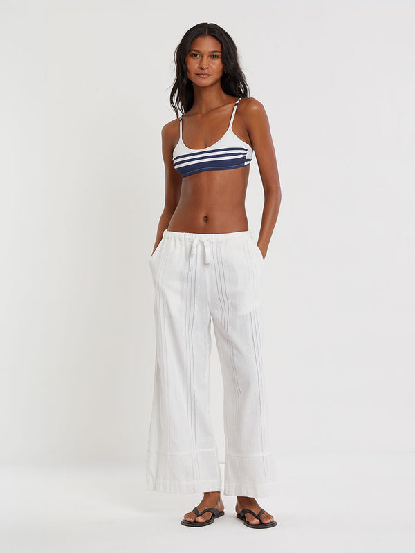 Woman wearing lemlem ASHA striped bikini top and lemlem handwovem DESTA Pants  on a plain background