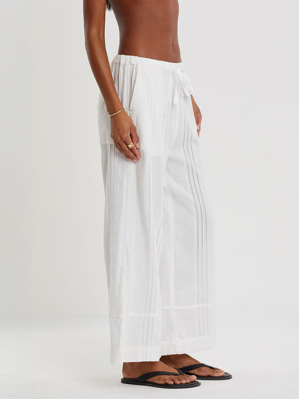 Woman wearing lemlem ASHA striped bikini top and lemlem handwovem DESTA Pants  on a plain background