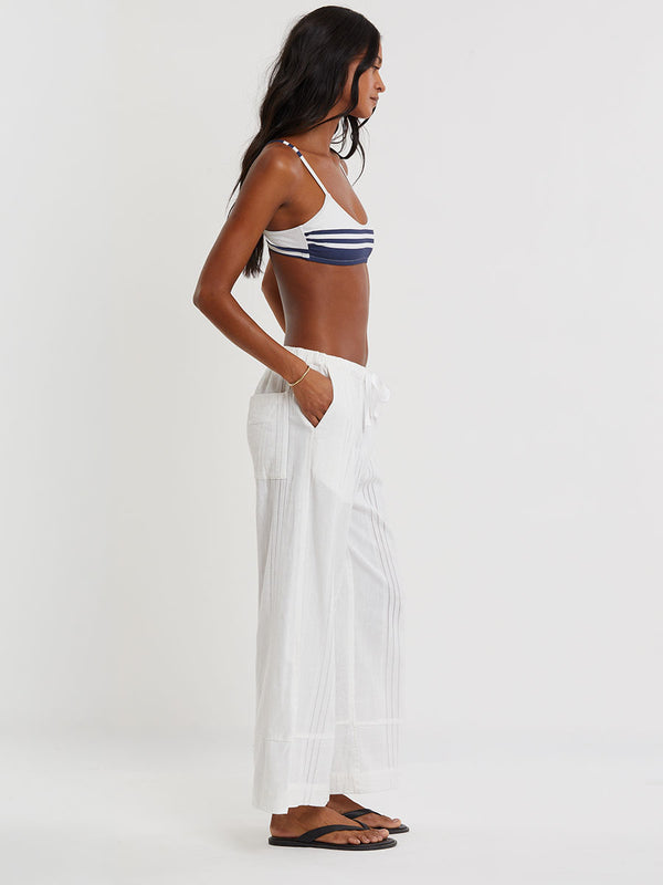 Woman wearing lemlem ASHA striped bikini top and lemlem handwovem DESTA Pants  on a plain background