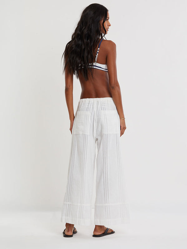 Woman wearing lemlem ASHA striped bikini top and lemlem handwovem DESTA Pants  on a plain background