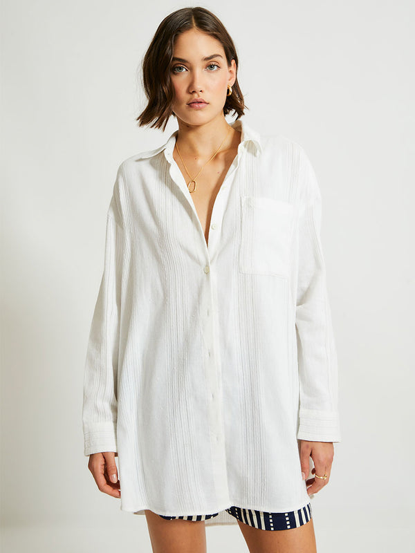 Woman Standing Wearing lemlem MARIAM Shirt featuring white color and shorts featuring striped and dotted pattern on silky navy background