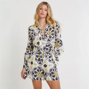 Woman standing wearing lemlem linen AZMERA Blouse and FAIZAH Shorts featuring floral inspired print 