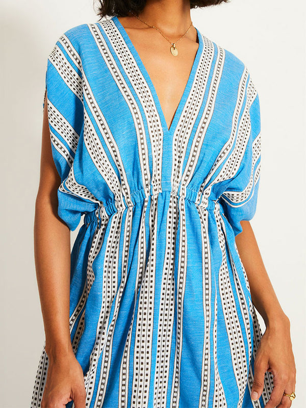 Close up on a Woman Standing Wearing lemlem ALEM Dress featuring classic Amira pattern with small geometric bands that float on a rich teal blue ground