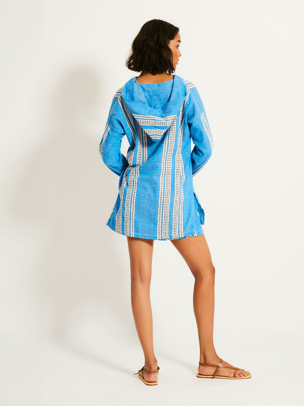 Back of a Woman Standing Wearing lemlem HENOK Hoodie featuring classic Amira pattern with small geometric bands that float on a rich teal blue ground