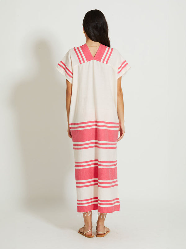 Back of a Woman Standing Wearing lemlem GASIRA | V Neck Caftan featuring bold two-tone stripe pattern in watermelon pink and soft rosy cream