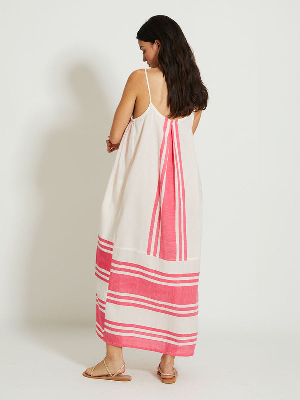 Back of a Woman Standing Wearing lemlem NIA | Slip Dress featuring bold two-tone stripe pattern in watermelon pink and soft rosy cream