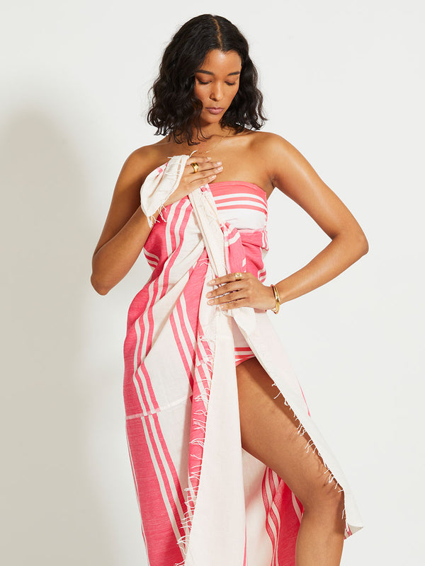 Woman Standing Wearing lemlem TALAKI | Sarong featuring bold two-tone stripe pattern in watermelon pink and soft rosy cream