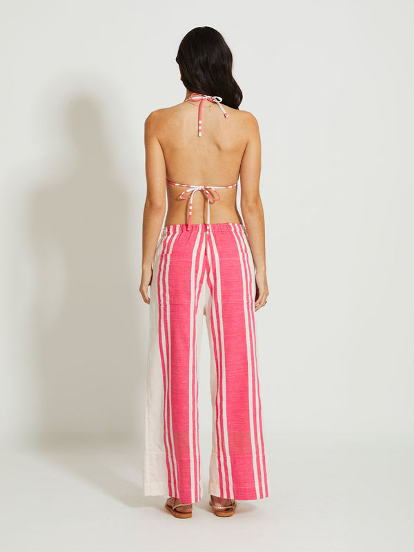 Back of a Woman Standing Wearing lemlem DESTA | Pants featuring bold two-tone stripe pattern in watermelon pink and soft rosy cream