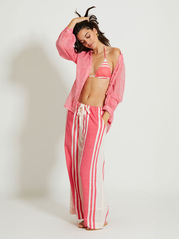 Woman Standing Wearing lemlem DESTA | Pants featuring bold two-tone stripe pattern in watermelon pink and soft rosy cream
