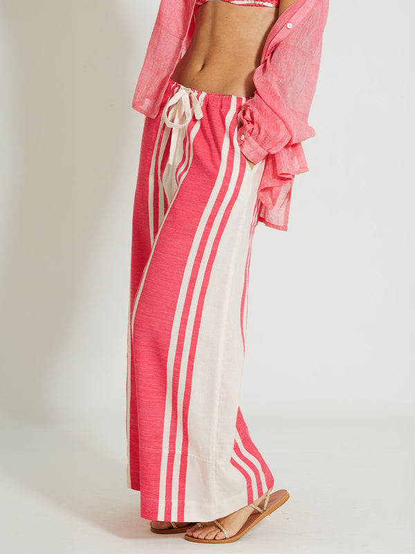 Close up on a Woman Standing Wearing lemlem DESTA | Pants featuring bold two-tone stripe pattern in watermelon pink and soft rosy cream