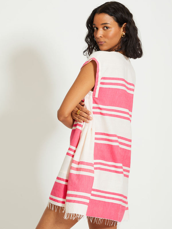 Side shot of a Woman Standing Wearing lemlem ELINA | Caftan featuring bold two-tone stripe pattern in watermelon pink and soft rosy cream