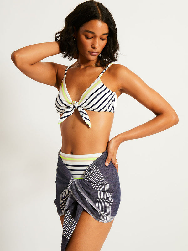 Woman Standing Wearing lemlem SARA Tie Front Top featuring an ivory ground with navy stripes, accented by khaki and citron hues
