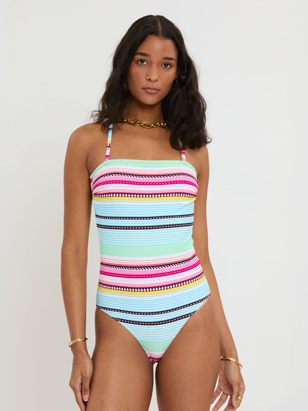 Woman wearing a colorful striped swimsuit against a white background