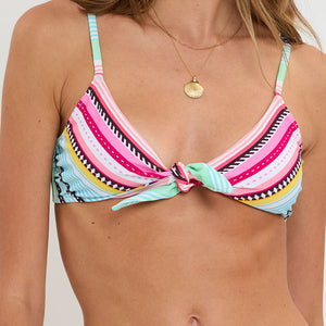 Colorful striped bikini top worn by a person on a plain background