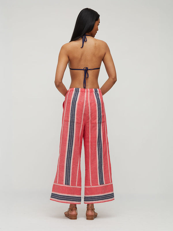 A woman shown from the back wearing wide-leg cropped pants with vertical red, navy, and white stripes, paired with a matching navy halter top, against a light gray studio background.