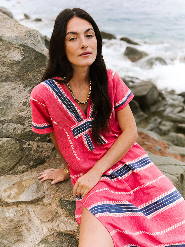 A woman modeling a red and navy striped  lemlem handwoven GASIRA Caftan with a high side slit