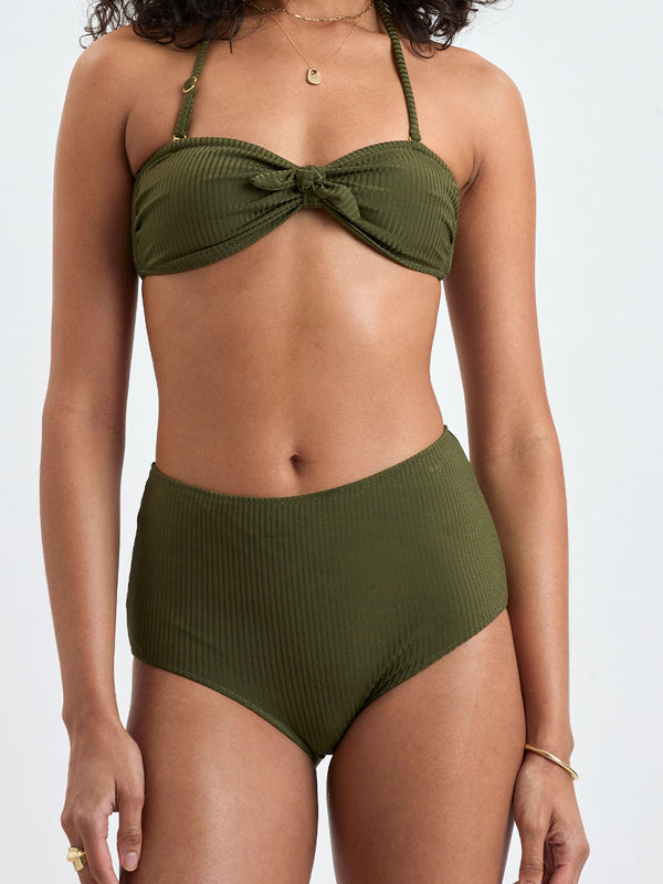 Close up on a Woman wearing lemlem ELSI High Waist Bottom and AVA Bandeau Bikini Top featuring a rich olive green color and a soft, silky ribbed texture fabric