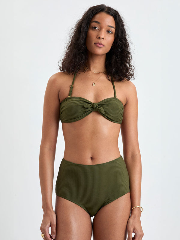 Woman wearing lemlem ELSI High Waist Bottom and AVA Bandeau Bikini Top featuring a rich olive green color and a soft, silky ribbed texture fabric