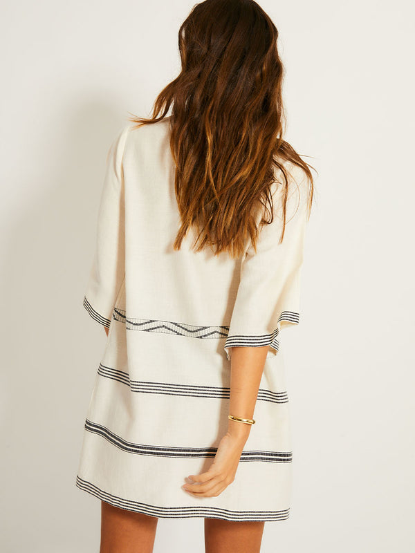 Back of a Woman Standing Wearing lemlem BELKIS Caftan featuring  black intricate stripes and a Tibeb wave band on a soft vanilla ground