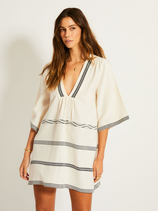 Woman Standing Wearing lemlem BELKIS Caftan featuring  black intricate stripes and a Tibeb wave band on a soft vanilla ground