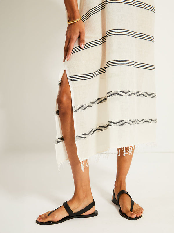 Close up on Woman's legs Standing Wearing lemlem DALILA Caftan featuring  black intricate stripes and a Tibeb wave band on a soft vanilla ground