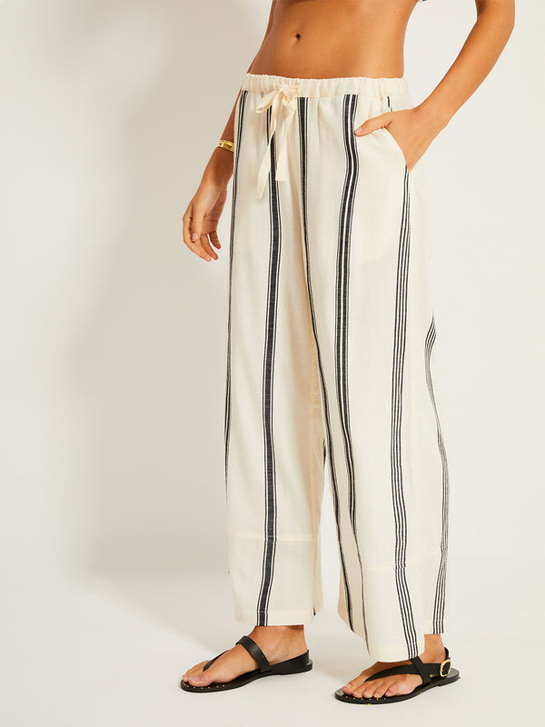 Close up on a Woman Standing Wearing lemlem DALILA Caftan featuring  black intricate stripes and a Tibeb wave band on a soft vanilla ground