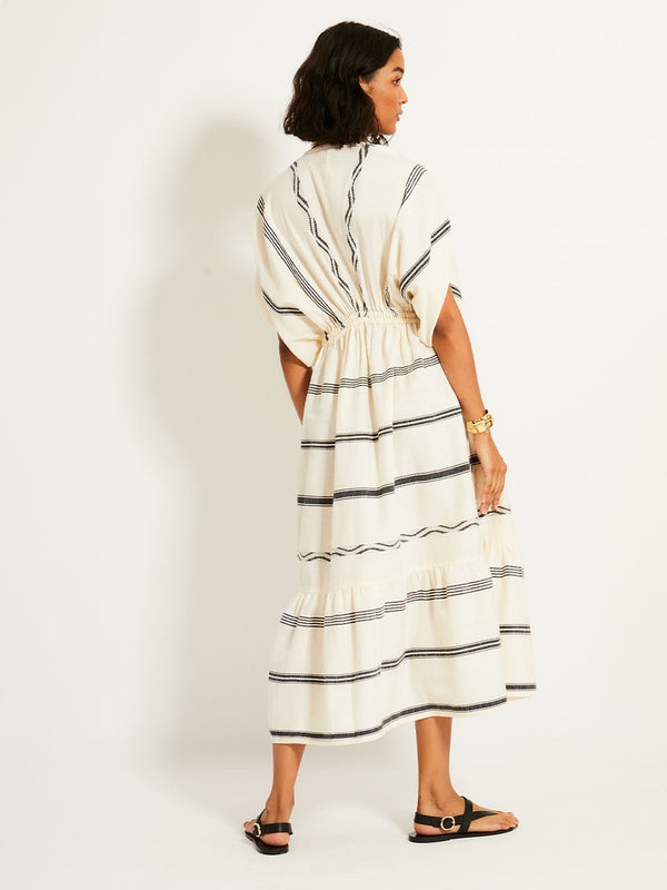 Back of a Woman Standing Wearing lemlem LEILA Dress featuring  black intricate stripes and a Tibeb wave band on a soft vanilla ground