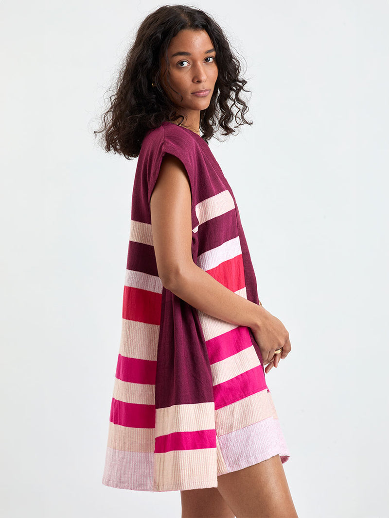 Woman standing wearing lemlem ELINA Caftan featuring a striking color-block combination of vivid magenta, scarlet, and burgundy colors.
