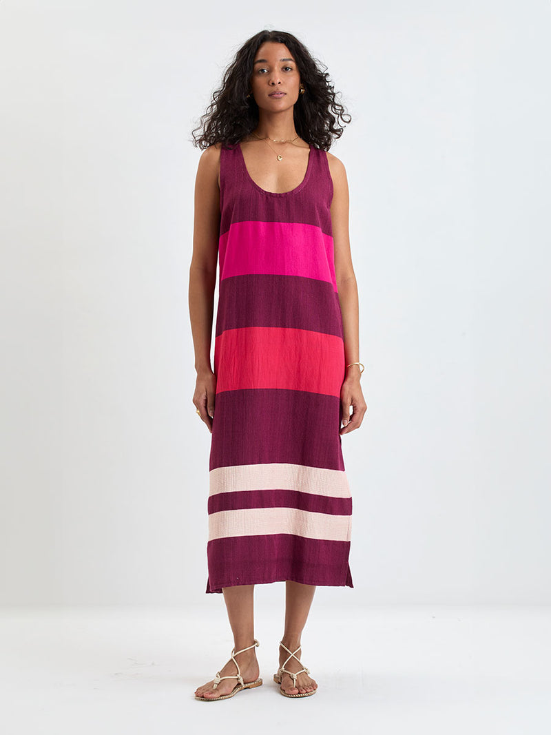 Woman standing wearing lemlem LILIAN Tank Dress featuring a striking color-block combination of vivid magenta, scarlet, and burgundy colors.