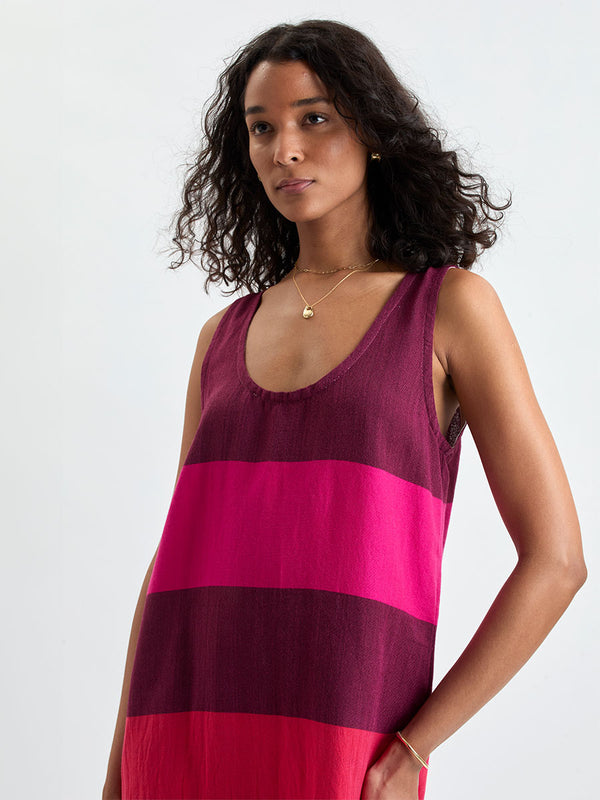 Woman standing wearing lemlem LILIAN Tank Dress featuring a striking color-block combination of vivid magenta, scarlet, and burgundy colors.