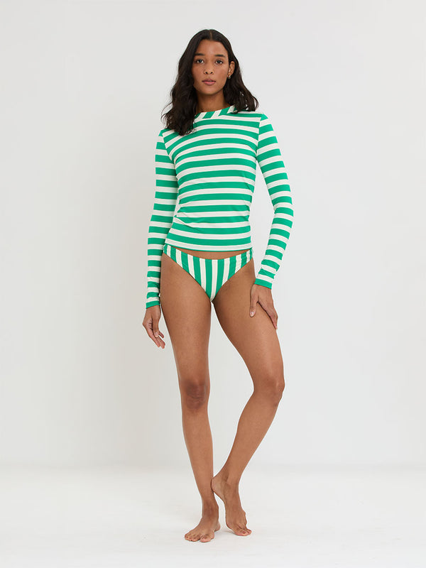 Woman Standing Wearing lemelm AZEB Rashguard and MERON Brief Bottom featuring classic cabana stripe in classic green, accented by soft ivory.